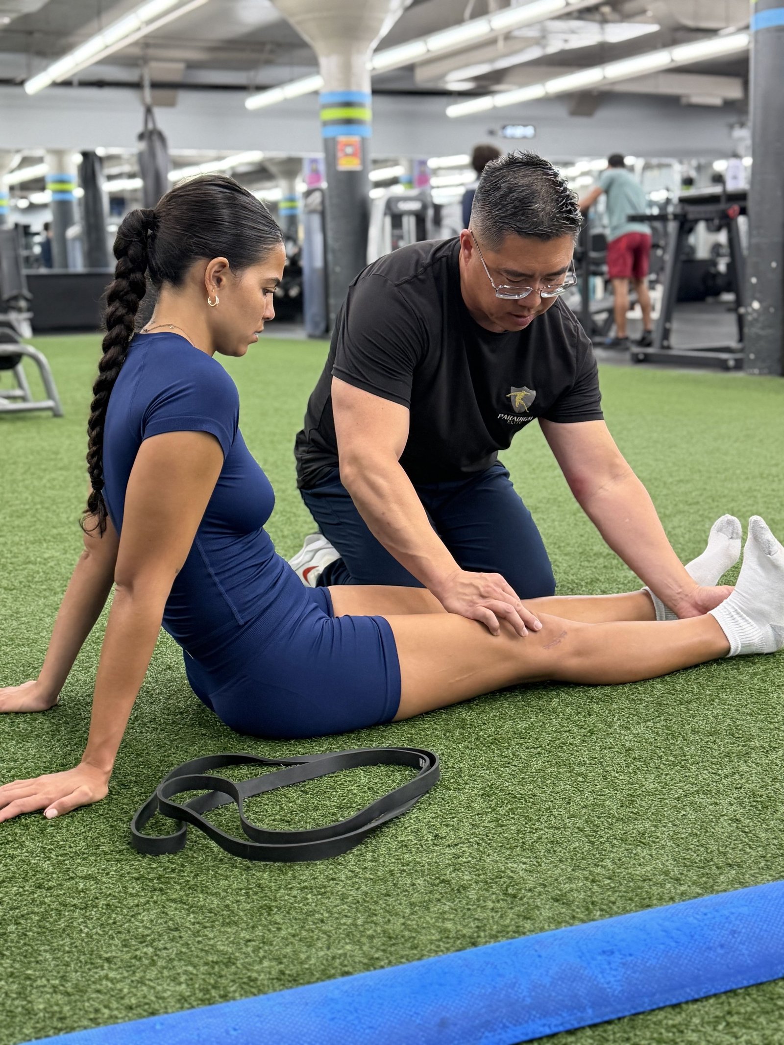 Dr. Stu palpating a client's hamstring during a seated flexibility assessment